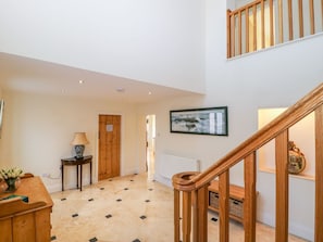 A spacious hallway with a wooden staircase, a framed picture on the wall, and a small table with a lamp. - Tuft House (York)
