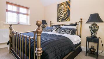 A bedroom with a bed, a window, a painting, a lamp, and a nightstand.