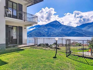 Ein zweigeschossiges Gebäude mit einem Balkon, der auf einen See und Berge blickt.