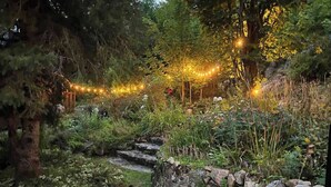 A garden with a stone pathway, dense foliage, and string lights. - 19th-century chalet with all modern comforts, 2 bedrooms, 1 bathroom (Saint-Barthélemy)