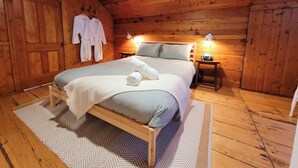 A wooden-paneled room with a bed, two bedside lamps, and a wooden nightstand. - 19th-century chalet with all modern comforts, 2 bedrooms, 1 bathroom (Saint-Barthélemy)