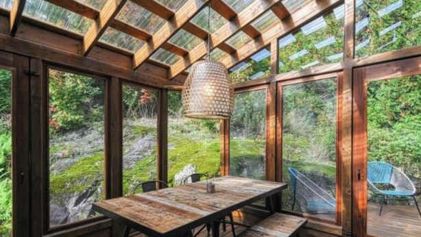 A wooden interior with a table and chairs, large windows, and a hanging light fixture. - 19th-century chalet with all modern comforts, 2 bedrooms, 1 bathroom (Saint-Barthélemy)