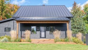 A modern two-story house with a dark roof, a front porch, and a well-maintained lawn. - 19th-century chalet with all modern comforts, 2 bedrooms, 1 bathroom (Saint-Barthélemy)