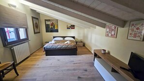 Une chambre à coucher avec un lit, un banc, une télévision et un radiateur.