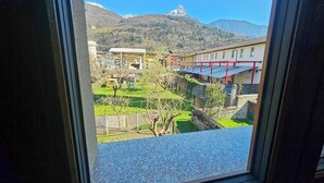 On voit, à travers une fenêtre, un bâtiment avec une montagne en arrière-plan.