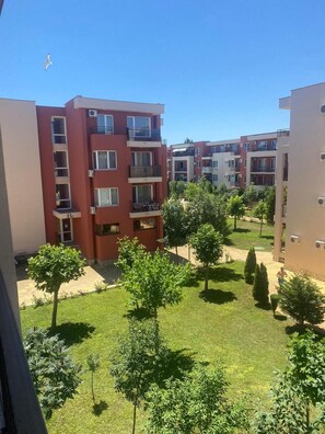 A residential building complex with multiple balconies, a well-maintained lawn, and a clear sky. - Pool View 2 Bed at Holiday Fort Club (Nessebar)