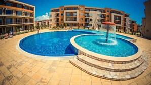 Ein Pool mit zentralem Wasserspiel, umgeben von einer gefliesten Terrasse.