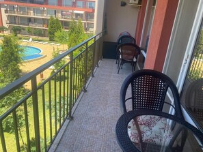 A balcony with a view of a swimming pool and a building with multiple balconies. - Pool View 2 Bed at Holiday Fort Club (Nessebar)