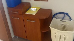 Ein Holzschrank mit einem blauen Behälter, einem Spiegel, einem Rauchverbotsschild und einem weißen Wäschekorb.