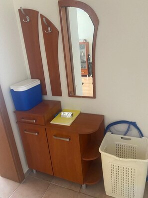 Ein Holzschrank mit einem blauen Behälter, einem Spiegel, einem Rauchverbotsschild und einem weißen Wäschekorb.