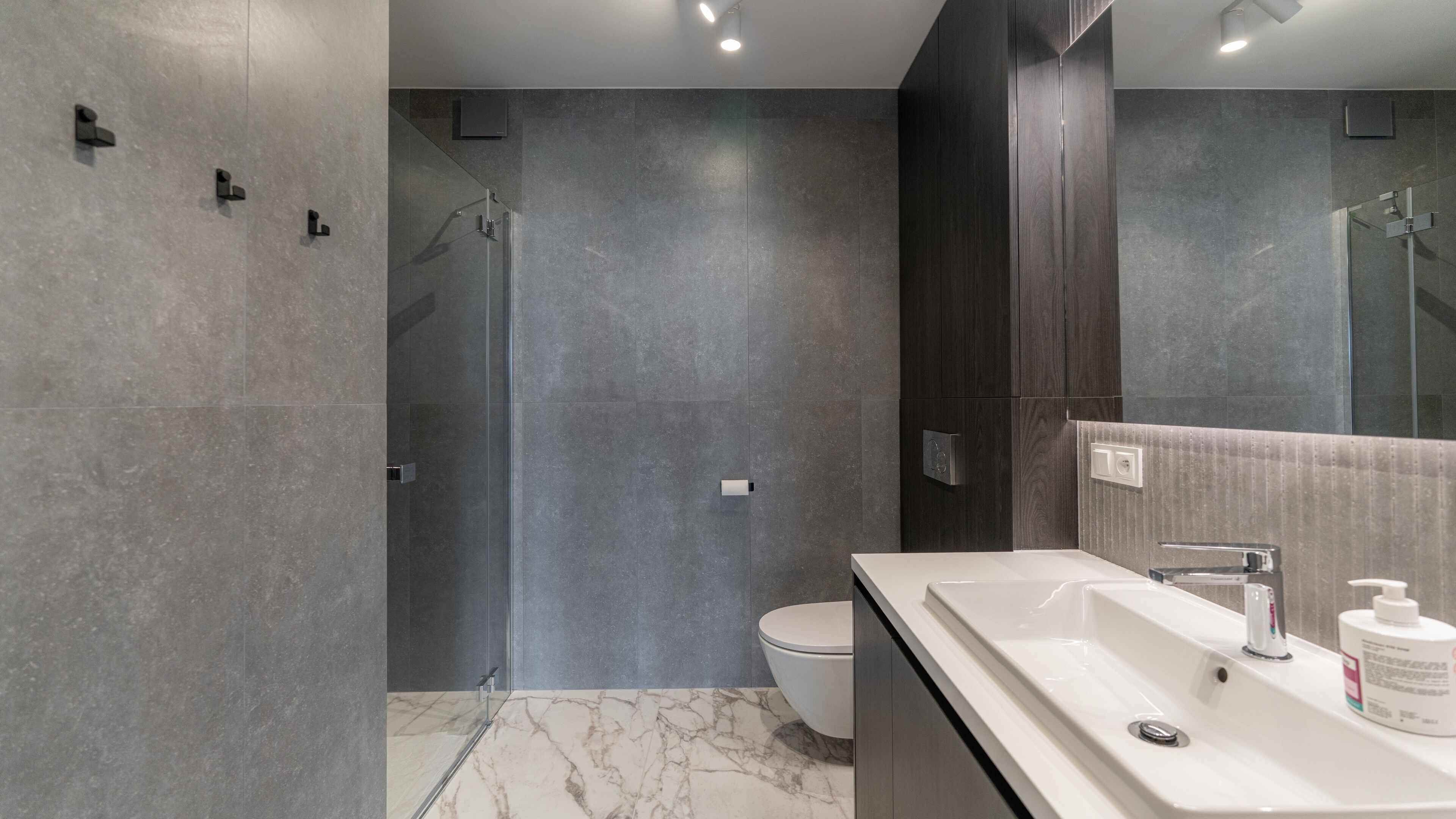 Un baño moderno con un espejo grande, un lavabo blanco y una zona de ducha.