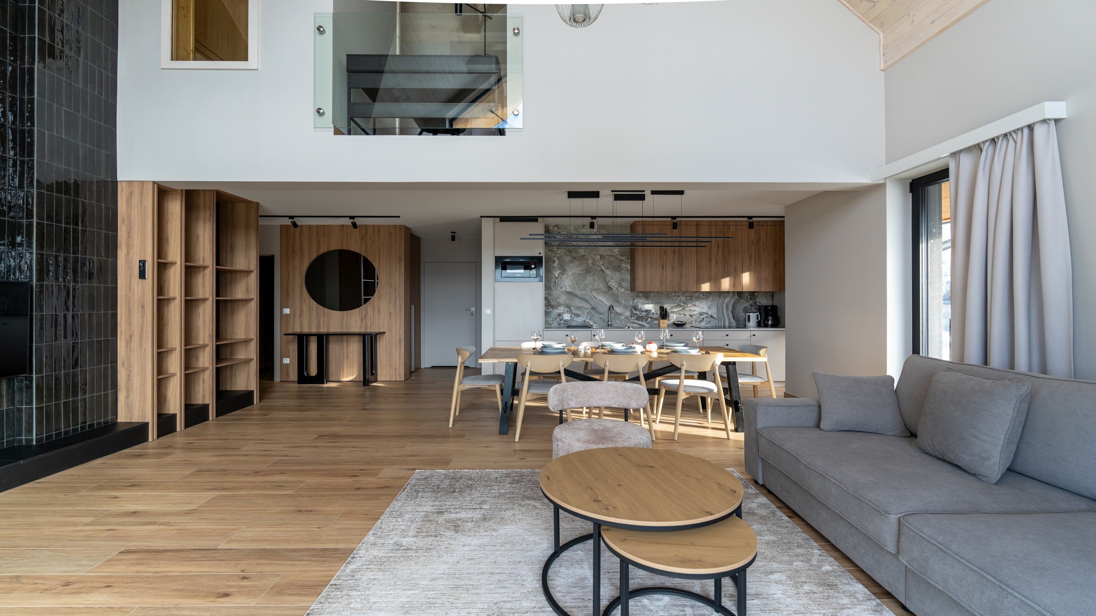 A modern living room with a sofa, two coffee tables, and a dining area with a table set for four.