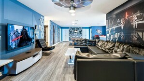 A modern living room with a large flat-screen TV, leather sofas, and Star Wars-themed decor. - Spacious 9-bedroom house in serene Kissimmee with AC (Kissimmee)