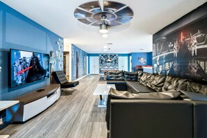 A modern living room with a large flat-screen TV, leather sofas, and Star Wars-themed decor. - Spacious 9-bedroom house in serene Kissimmee with AC (Kissimmee)
