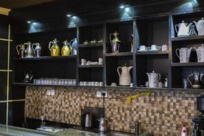 A kitchen with shelves of kitchenware, a tiled backsplash, and a coffee machine. - Quiet Rooms 8 (Riyadh)
