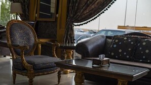 A room with a classic blue armchair, a dark sofa with polka dots, and a glass coffee table. - Quiet Rooms 8  (Riyadh)