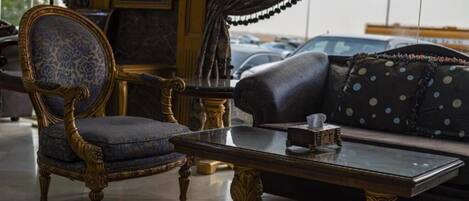 A room with a classic blue armchair, a dark sofa with polka dots, and a glass coffee table.