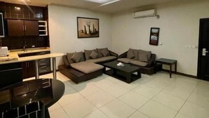 A modern living room with a sofa set, a dining table, and a kitchen area. - Quiet Rooms 8  (Riyadh)