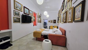 Ein Hotelzimmer mit einem Bett, einem Fernseher, einer roten Wand und mehreren gerahmten Bildern an den Wänden.