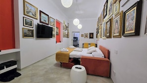 Ein Hotelzimmer mit einem Bett, einem Fernseher, einer roten Wand und mehreren gerahmten Bildern an den Wänden.