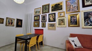 Ein Zimmer mit Esstisch, Stühlen, einem roten Sofa und einer Wand mit gerahmten Kunstwerken.