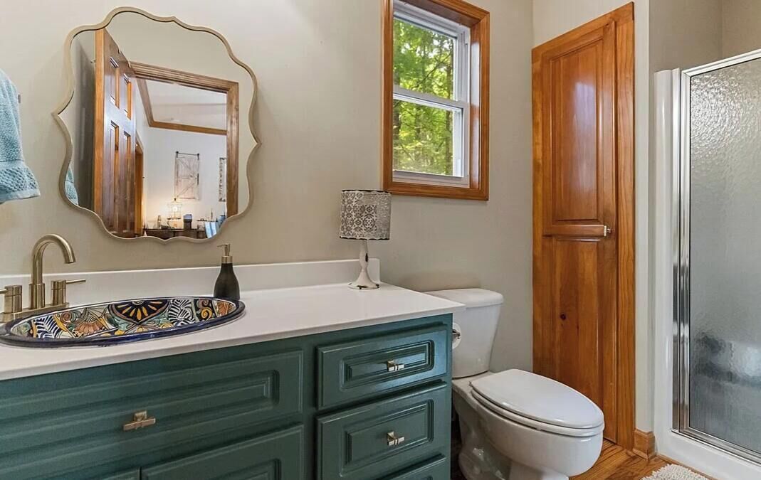 A bathroom with a vanity, a mirror, a toilet, and a shower area.