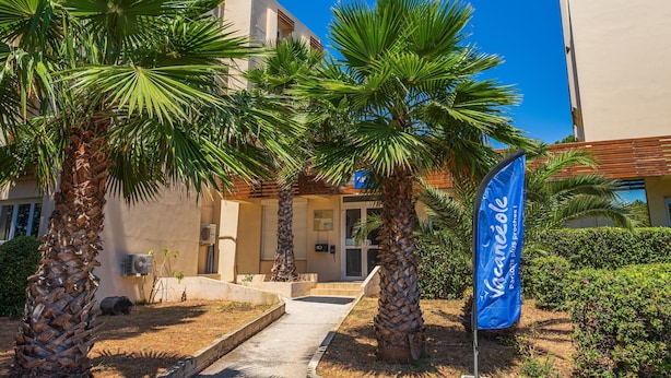 A building with palm trees, a blue flag, and a clear blue sky. - 4-guest AC Apartment Near Beach (La Londe-les-Maures)