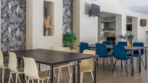 A dining area with a long table and chairs, a kitchen in the background, and a patterned wall. - 4-guest AC Apartment Near Beach (La Londe-les-Maures)