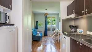 A compact kitchen with a microwave, a dishwasher, and a sink. There is a blue chair and a small table with a book. - 4-guest AC Apartment Near Beach (La Londe-les-Maures)