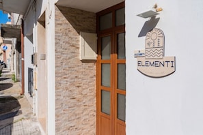 A building with a stone facade, a wooden door with glass panels, and a sign indicating 'ELEMENTI LUXURY HOUSE.' - Elementi Luxury House 'Terra' with Balcony, Wi-Fi and Air Conditioning (Otranto)