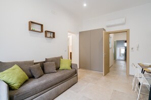 A living room with a sofa, a dining table with chairs, a wardrobe, and a hallway leading to another room. - Elementi Luxury House 'Terra' with Balcony, Wi-Fi and Air Conditioning (Otranto)
