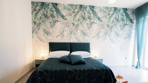 A bedroom with a bed, nightstands, a fruit bowl, and a tropical leaf wallpaper. - Villa Rossa (Agerola)
