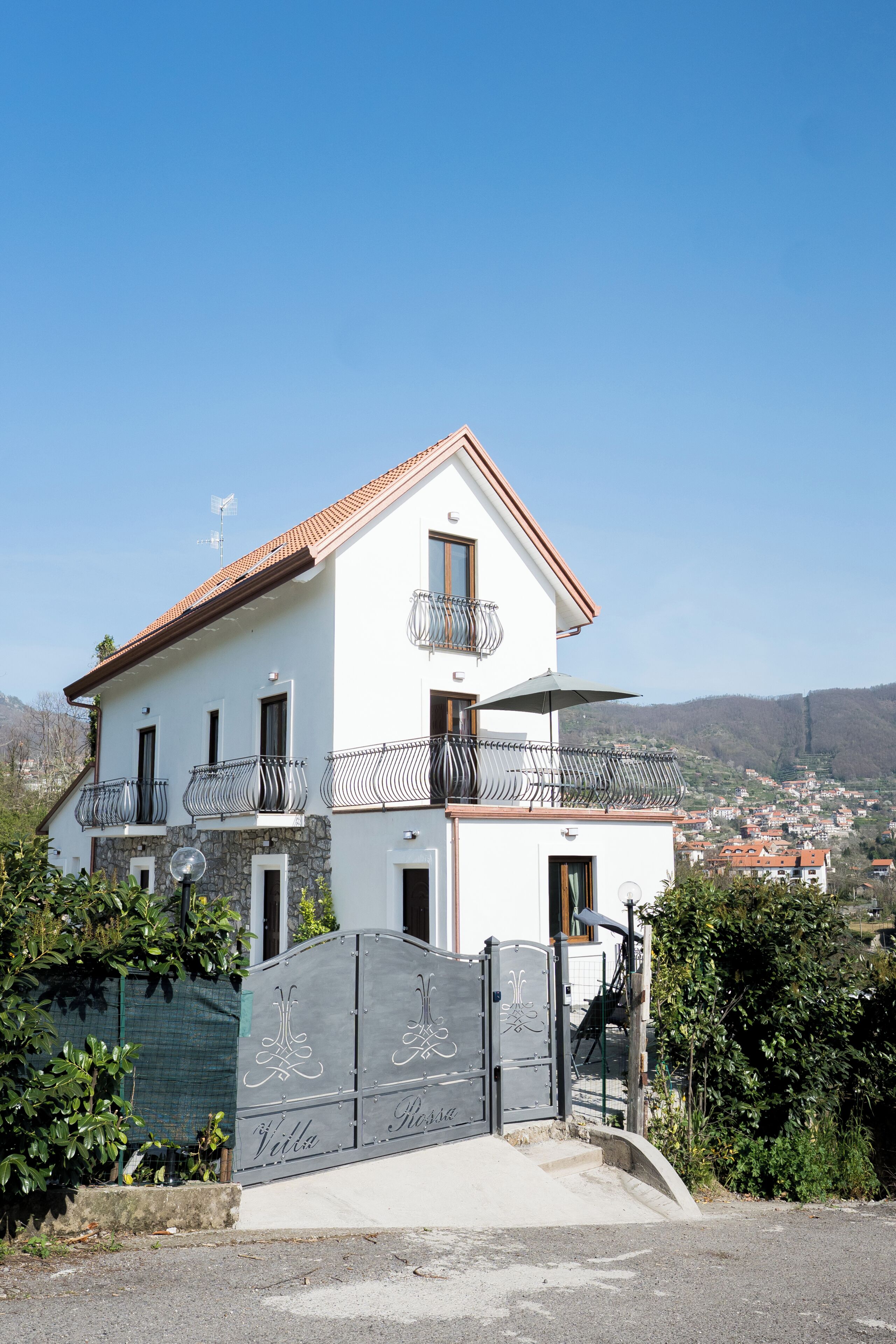 Ein zweistöckiges Haus mit Balkonen, einem Tor und Blick auf eine Stadt.