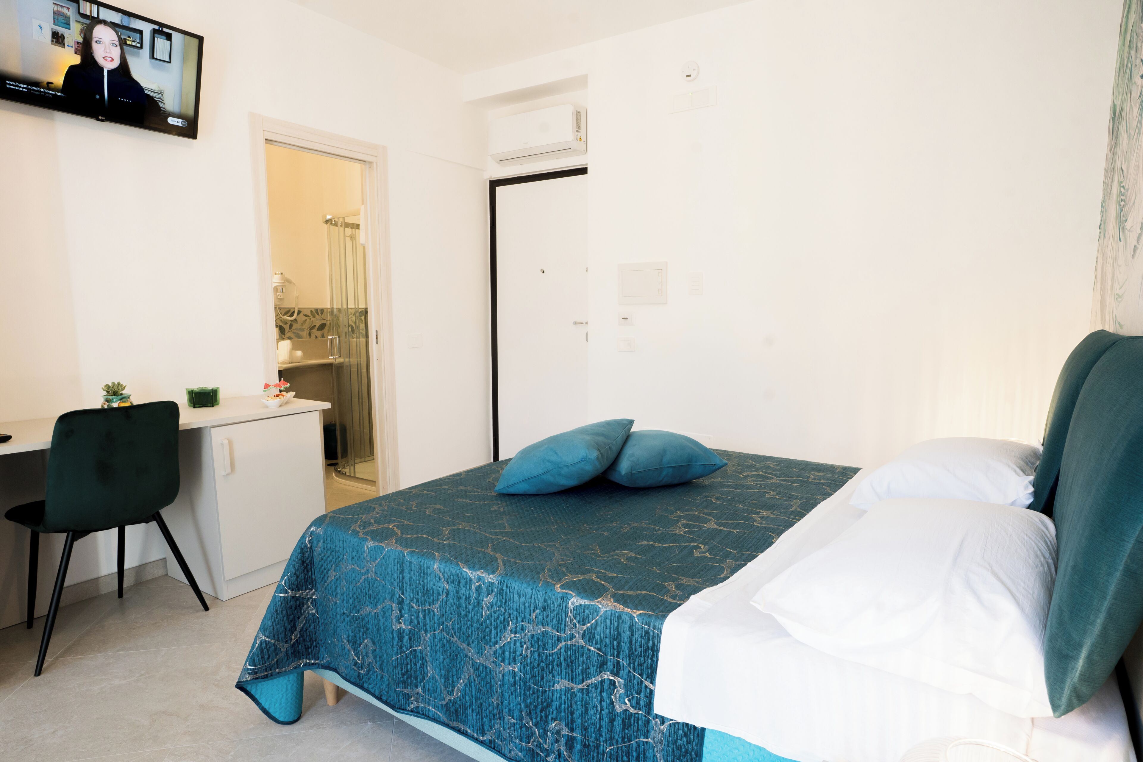 A bedroom with a bed, a desk, and a chair.