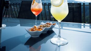 A table with two drinks and a bowl of nuts, set against a scenic mountain backdrop. - Villa Rossa (Agerola)