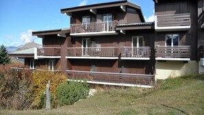 A multi-story building with balconies, a flat roof, and a mountainous backdrop. - Apartment by the Slopes in Les Deux Alpes (Les Deux Alpes)