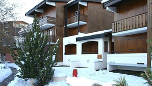 A multi-story building with wooden exterior and balconies, surrounded by snow. - Apartment by the Slopes in Les Deux Alpes (Les Deux Alpes)