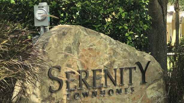 A large stone sign with the words 'Serenity Townhomes' engraved on it. - TinkerBell’s Smart Townhome  3BR & 3BA w/ a heated Pool 10 miles from Disney (Clermont)