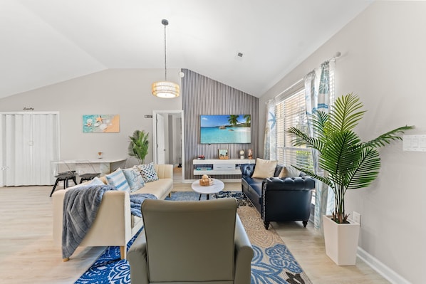 A modern living room with a sofa, armchairs, a coffee table, and a TV.