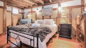 Un dormitorio con cama, cómoda, mesita de noche y un cuadro en la pared.