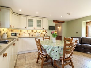 A kitchen with white cabinets, a microwave, and a dining table with chairs. - Carr House Farm (Chesterfield)