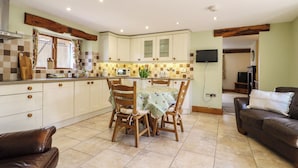 A kitchen with a dining table, chairs, a television, and a sofa.