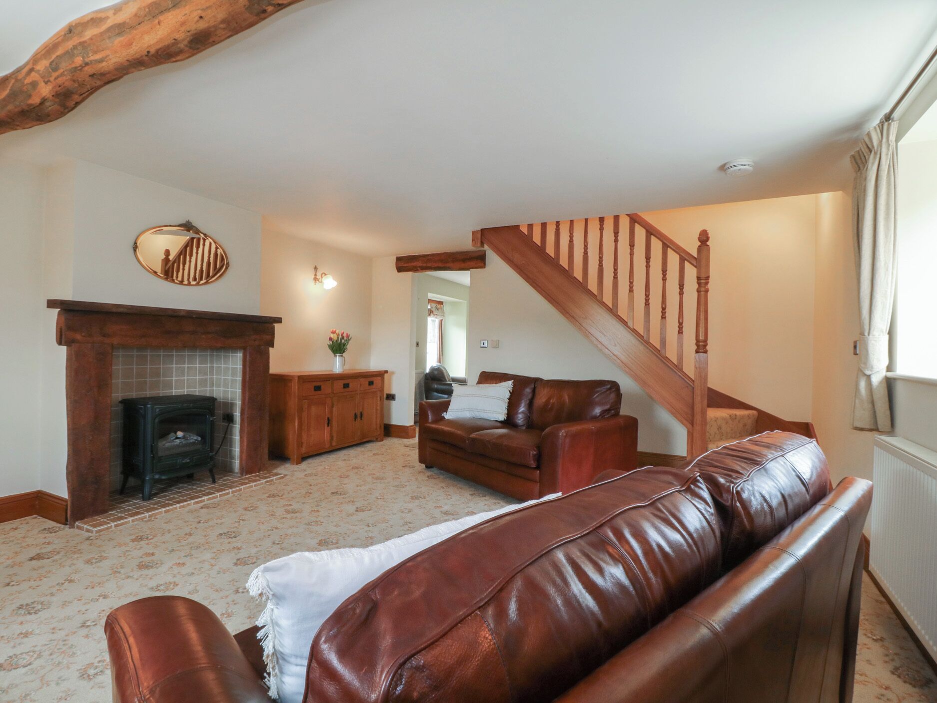 Una sala de estar con chimenea, escalera y sofá de cuero.