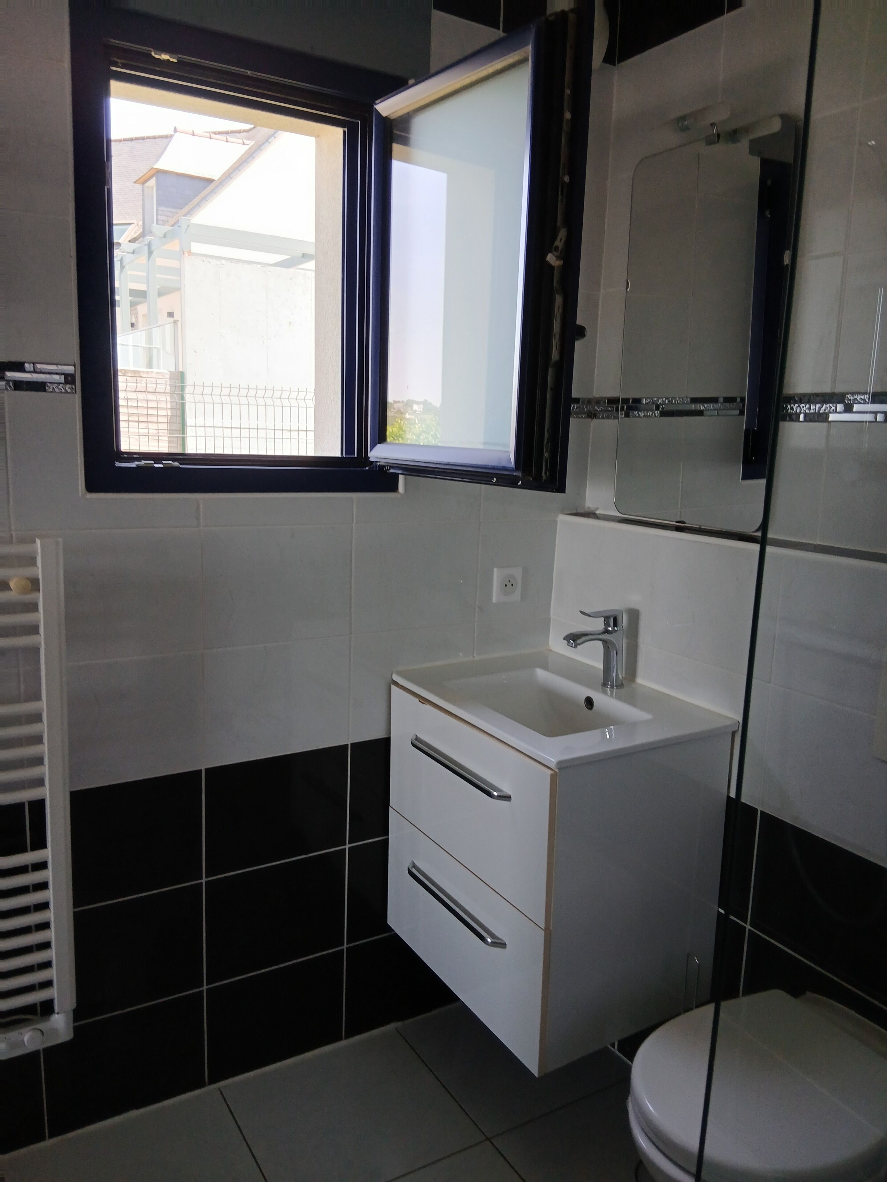 A bathroom with a white sink, a toilet, a window, and a mirror.