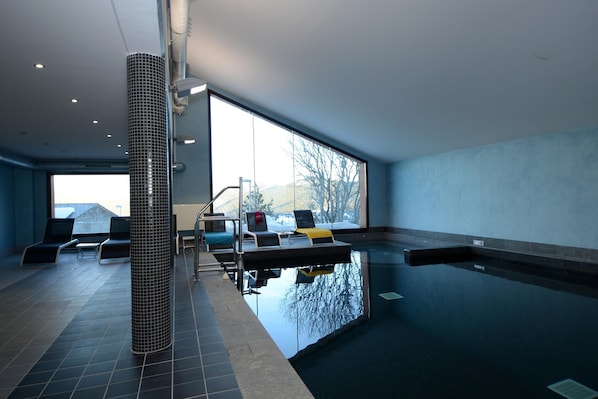 An indoor swimming pool with a view of mountains, lounge chairs, and a tiled floor. - Alpine Hideaway in Les Angles (Les Angles)