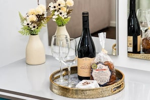 A table with a bottle of wine, glasses, a vase with flowers, and a tray with bread and cheese. - Horizon Pearl Madeira (Ponta do Sol)