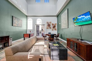 Ein geräumiger Wohnbereich mit Sofa, Couchtisch, Fernseher und Kunstwerken an den Wänden.