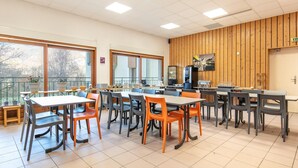 A dining area with tables and chairs, a wooden wall, and large windows. - Large 8-person Apartment in Giez (Giez)