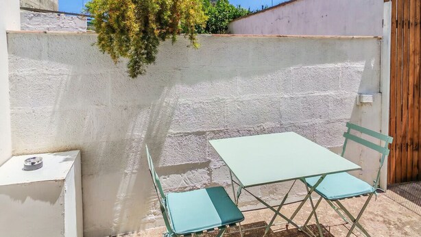 A patio with a table and chairs, a white wall, and a wooden gate. - The House of Aunts - Maglie (Maglie)