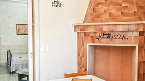 A room with a brick fireplace, a white table with chairs, and a stone-tiled floor. - The House of Aunts - Maglie (Maglie)